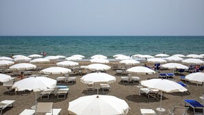 A beach with rows of white umbrellas and lounge chairs. - Hotel Miramare (Latina)