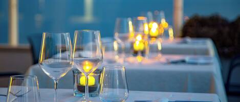 A dining table set with clear glasses, a candle, and a menu.