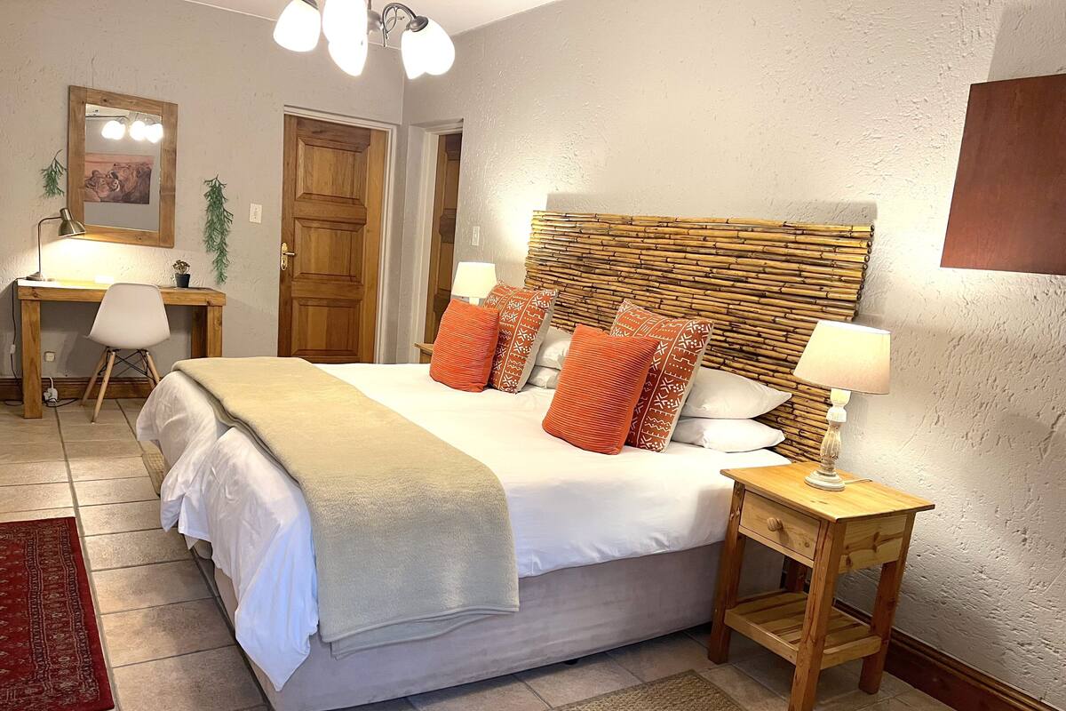 Un dormitorio ordenado con una cama grande, mesitas de noche con lámparas, un escritorio y una silla.