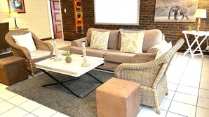 Una sala de estar con un sofá, dos sillones, una mesa de centro y una alfombra.