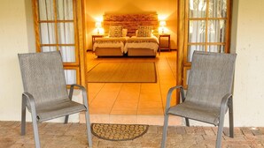 Habitación de hotel con dos camas, cabecero de madera y vistas al exterior.
