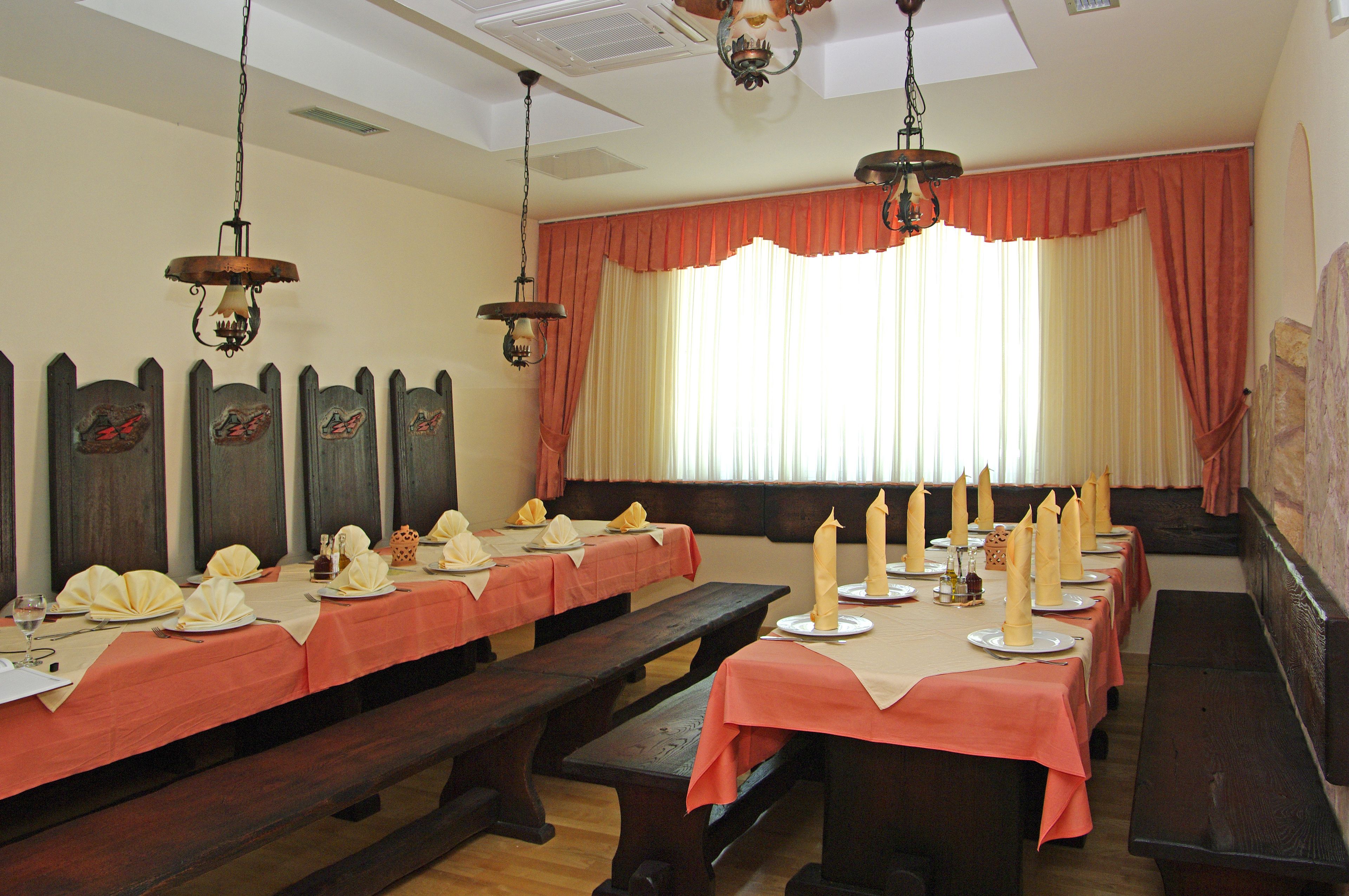 A long dining table set with multiple benches, candles, and table settings.