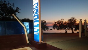 A pool area with a sign, wooden deck, and a view of the water. - Aparthotel Marina Gromela (Supetar)