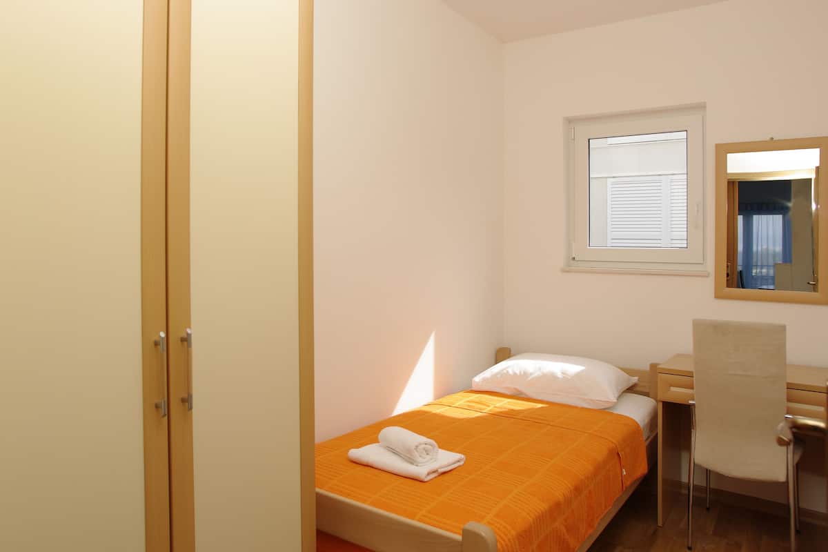Une chambre à coucher avec un lit, un bureau, une chaise, une armoire et une fenêtre.