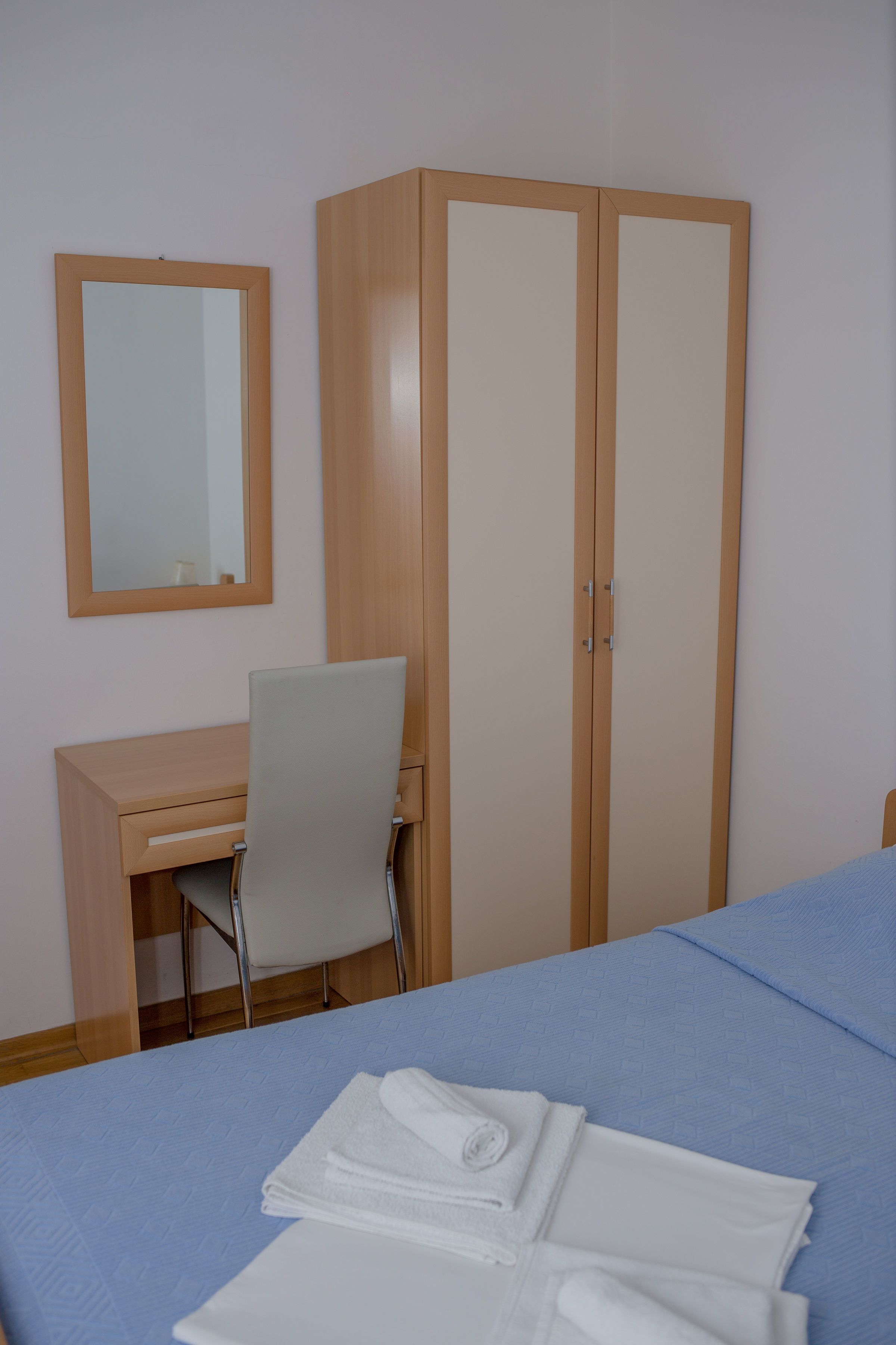 Ett hotellrum med en säng, ett skrivbord, en stol och en garderob.
