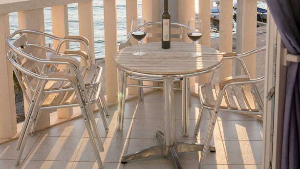 A balcony with a table and chairs, overlooking a body of water with boats. - Aparthotel Marina Gromela (Supetar)