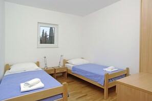 A small, clean room with two single beds, a desk, and a window. - Aparthotel Marina Gromela (Supetar)
