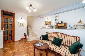 Una sala de estar con un sofá, una mesa de centro, una escalera y una estantería.