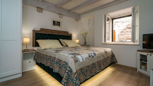 Un dormitorio con una cama grande, vigas de madera en el techo, una ventana con vistas y un mueble para televisión.