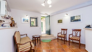 Una sala de estar acogedora con un sofá, dos sillones, una mesita y una escalera que lleva a un espacio al aire libre.