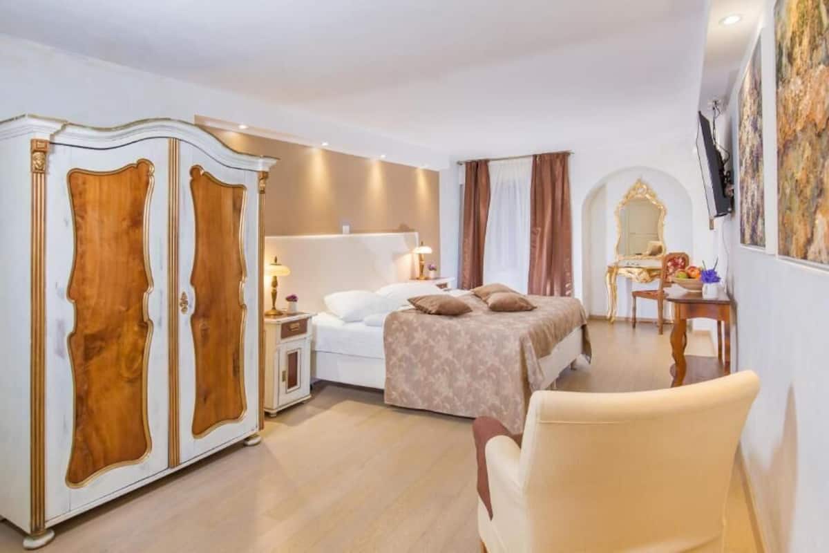 A hotel room with a bed, a wardrobe, a desk, and a chair.