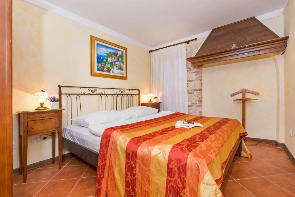 Un dormitorio con cama, mesita de noche, lámpara, un cuadro en la pared y techo de madera.