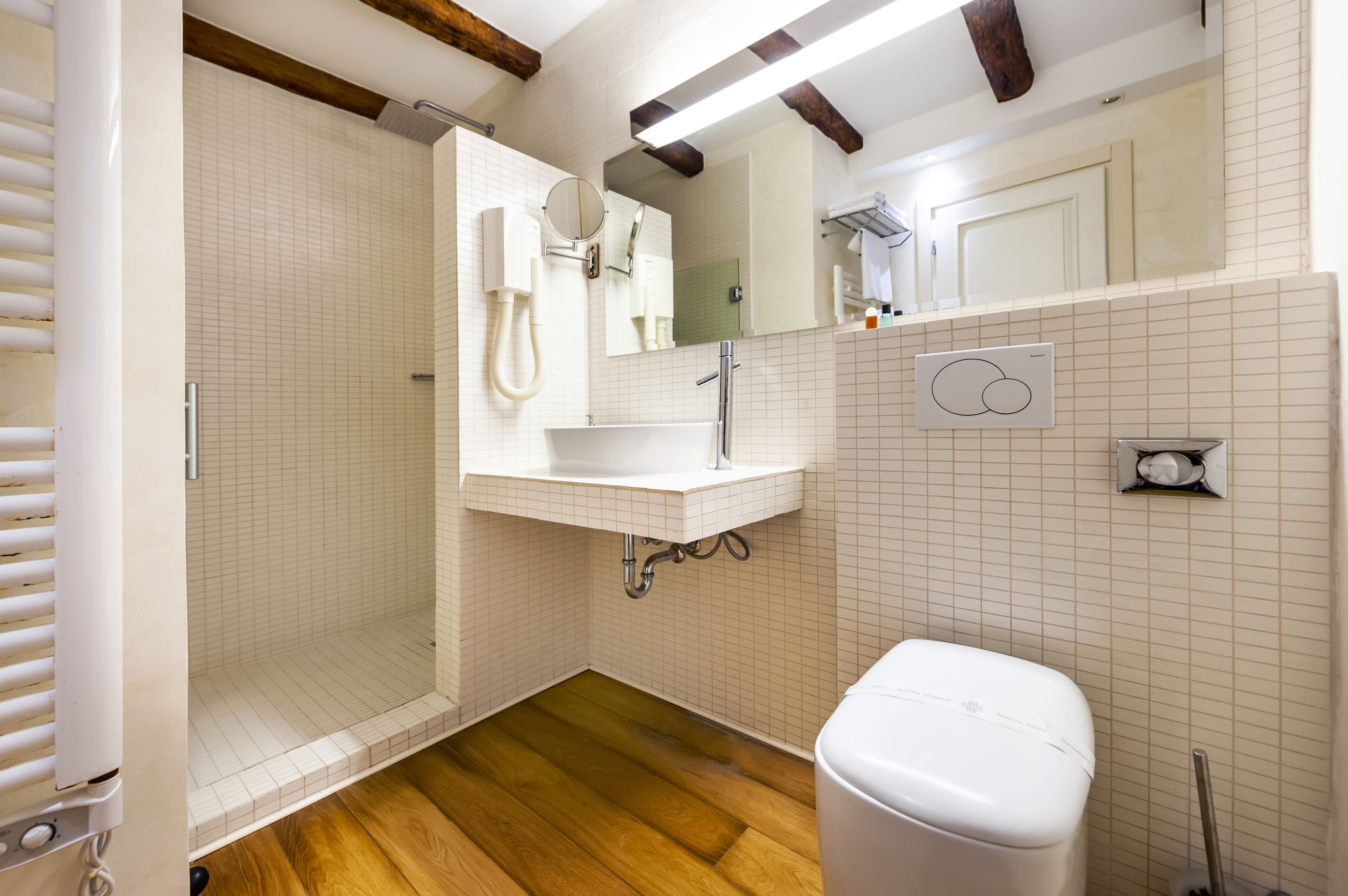 Un bagno con doccia, WC, lavandino e specchio.