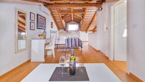 A bedroom with a sloped ceiling, a bed, a bedside table, and a window. - Hotel Villa Valdibora (Rovinj)