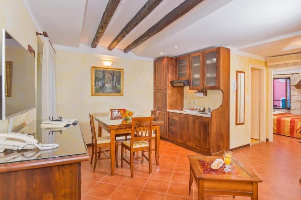 A compact hotel room with a dining area, wooden cabinets, and a tiled floor.