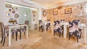 A dining area with stone walls, a clock, and framed pictures. - Hotel Villa Valdibora (Rovinj)