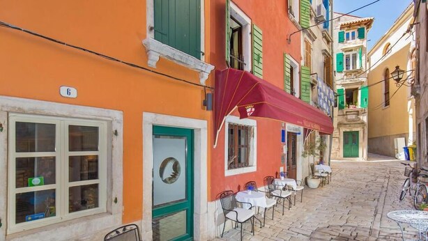 A narrow cobblestone street with outdoor seating and a red awning. - Hotel Villa Valdibora (Rovinj)
