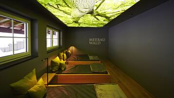 A room with three beds, a skylight, and a wall-mounted sign reading "MEERAU WALD".