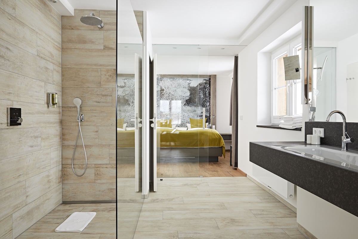Une salle de bain moderne avec une douche à parois de verre, un grand miroir et un lavabo sur un plan de toilette foncé.