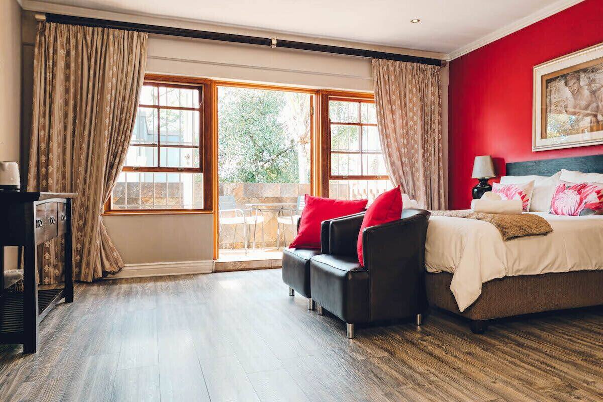 A hotel room with a bed, a sofa, a desk, and a view of the outdoors.