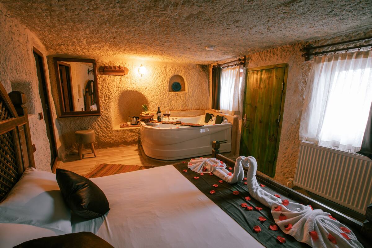 A room with a large bed, a bathtub, and a wooden door.