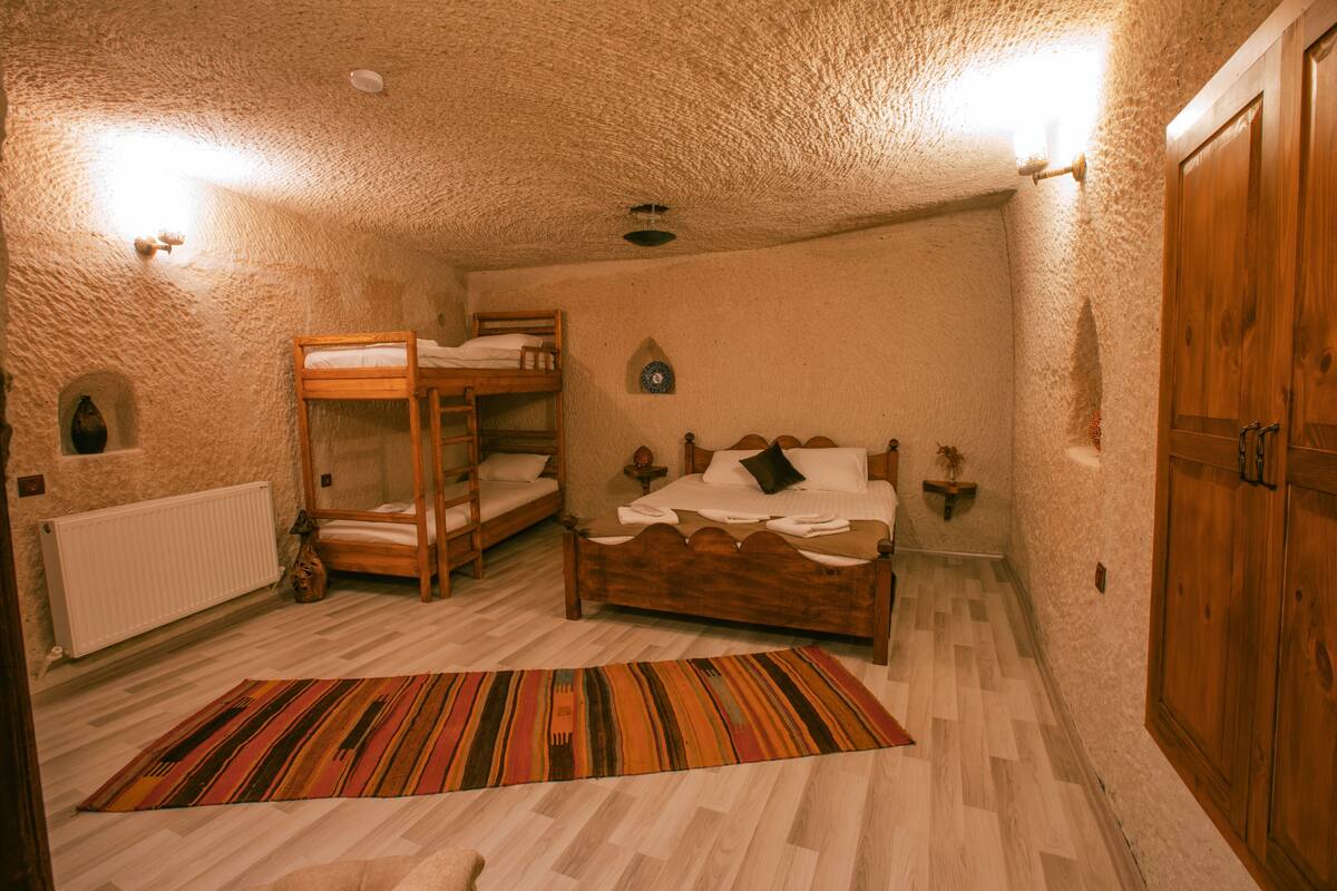 A room with a bunk bed, a single bed, a wooden wardrobe, and a radiator.