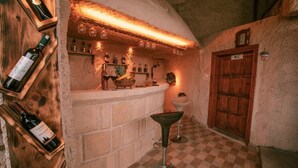 A bar area with a checkered floor, wooden bar counter, and wine bottles. - Mia Cappadocia Cave Hotel (Nevsehir)
