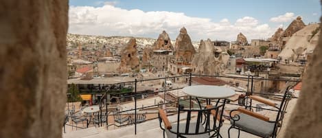 Terraço com área de estar ao ar livre com vista para uma cidade e formações rochosas características.