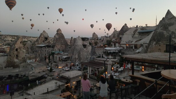 A view of a city with unique rock formations and a café area with outdoor seating. - Mia Cappadocia Cave Hotel (Nevsehir)