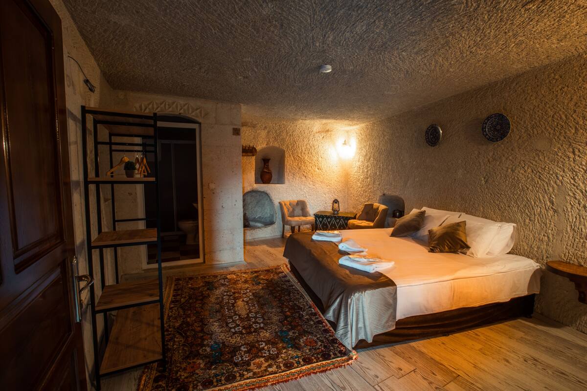 A bedroom with a bed, a wooden bench, a rug, and a shelf with items.