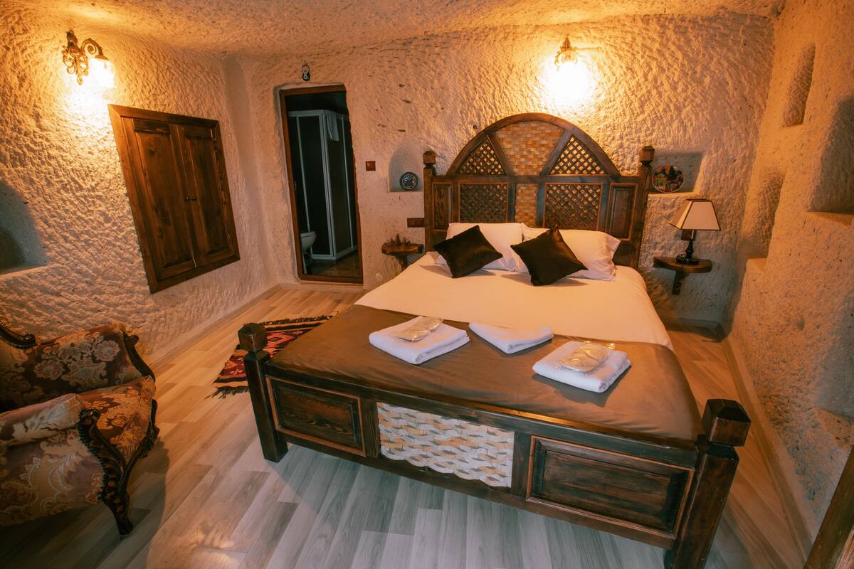 A bedroom with a wooden bed, a nightstand, a lamp, and a chair.