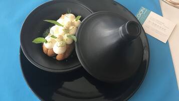 A black plate with a dessert on a blue tablecloth.