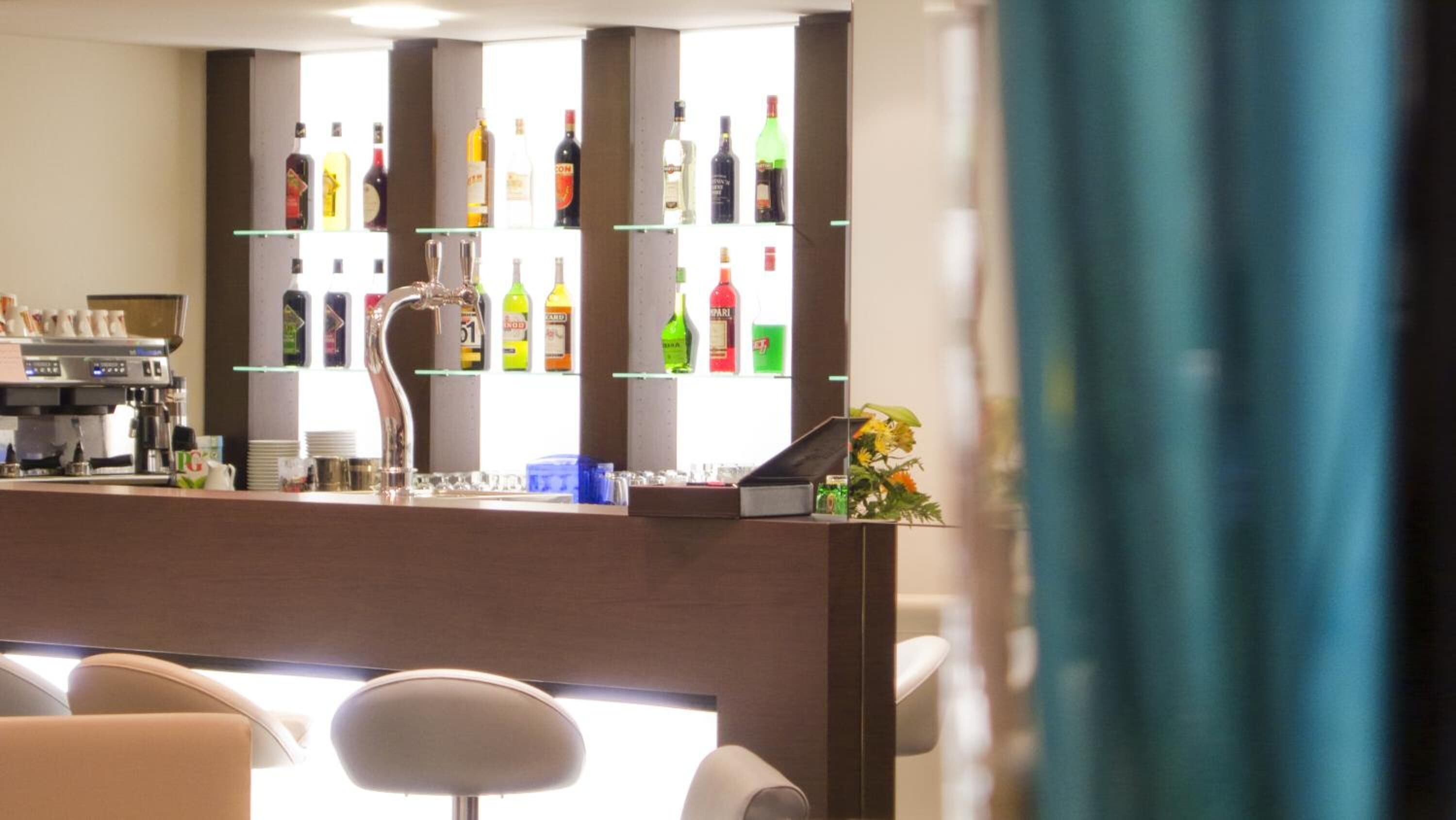 A bar area with a coffee machine and a variety of liquor bottles on shelves.