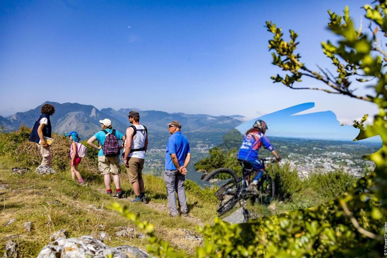 Un grupo de personas caminando por un sendero de montaña, con vistas a un valle y montañas al fondo.