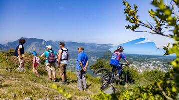 Un grupo de personas caminando por un sendero de montaña, con vistas a un valle y montañas al fondo.