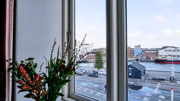 Blick aus dem Fenster auf eine Stadtlandschaft mit Fluss, Gebäuden und einem Anleger.