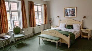 A classic bedroom with a bed, a chair, a bedside table, and a radiator.