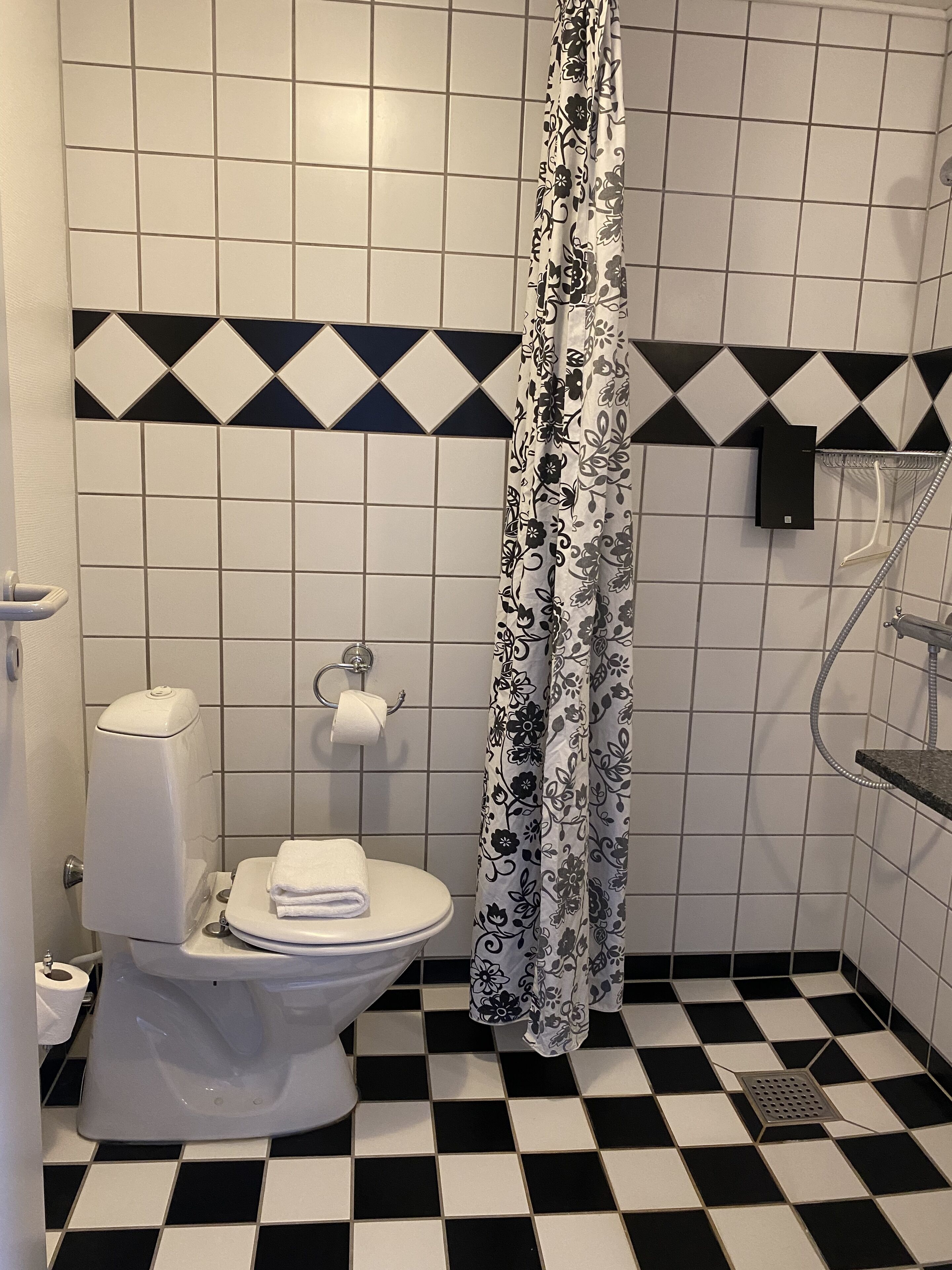 Un baño con inodoro, ducha y piso de baldosas.