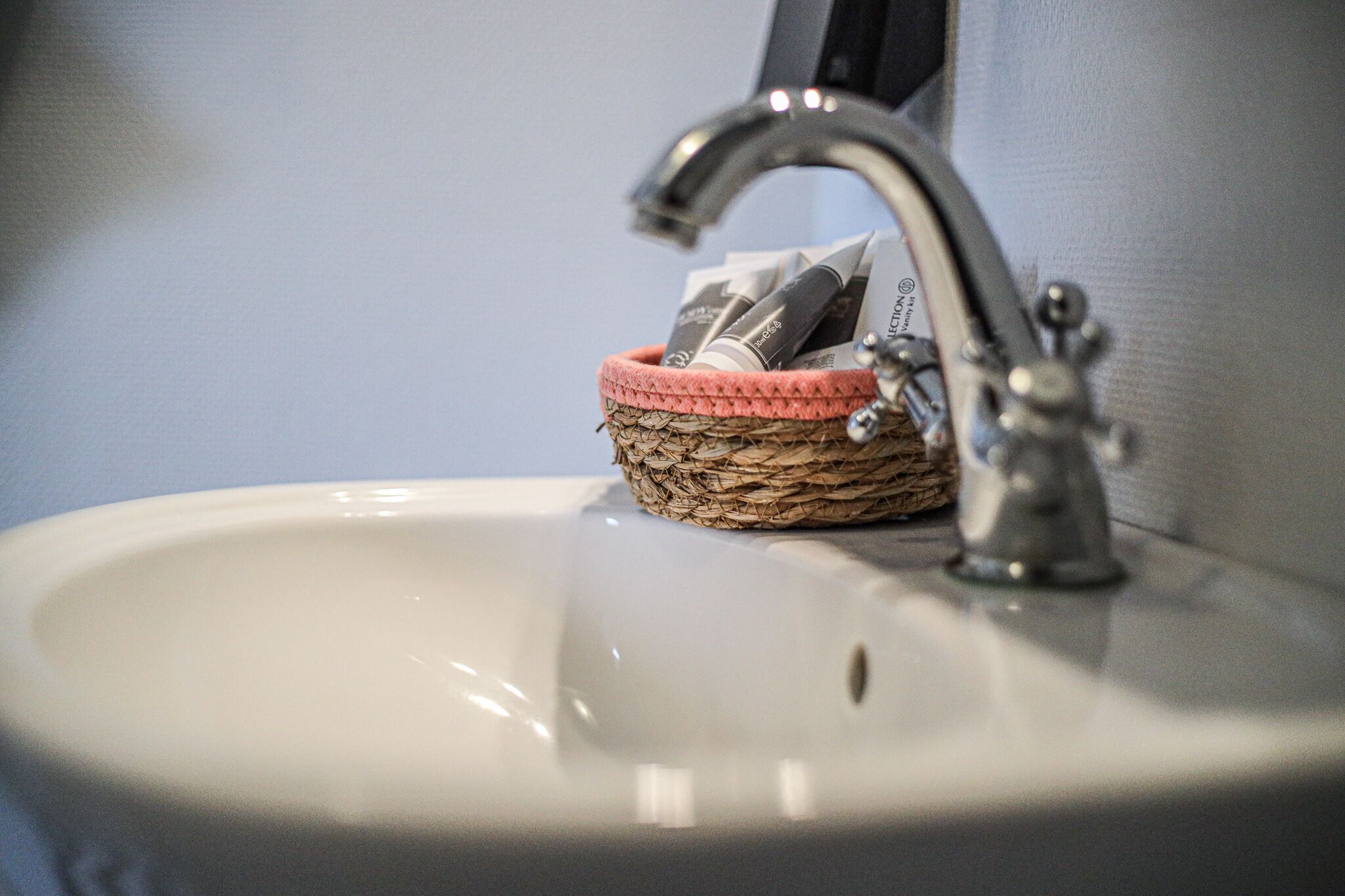 A bathroom sink with a woven basket containing toiletries.