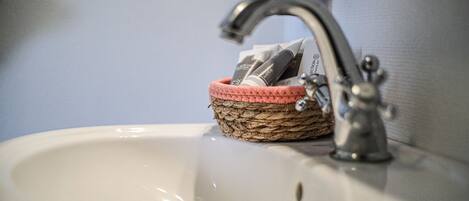 A bathroom sink with a woven basket containing toiletries.