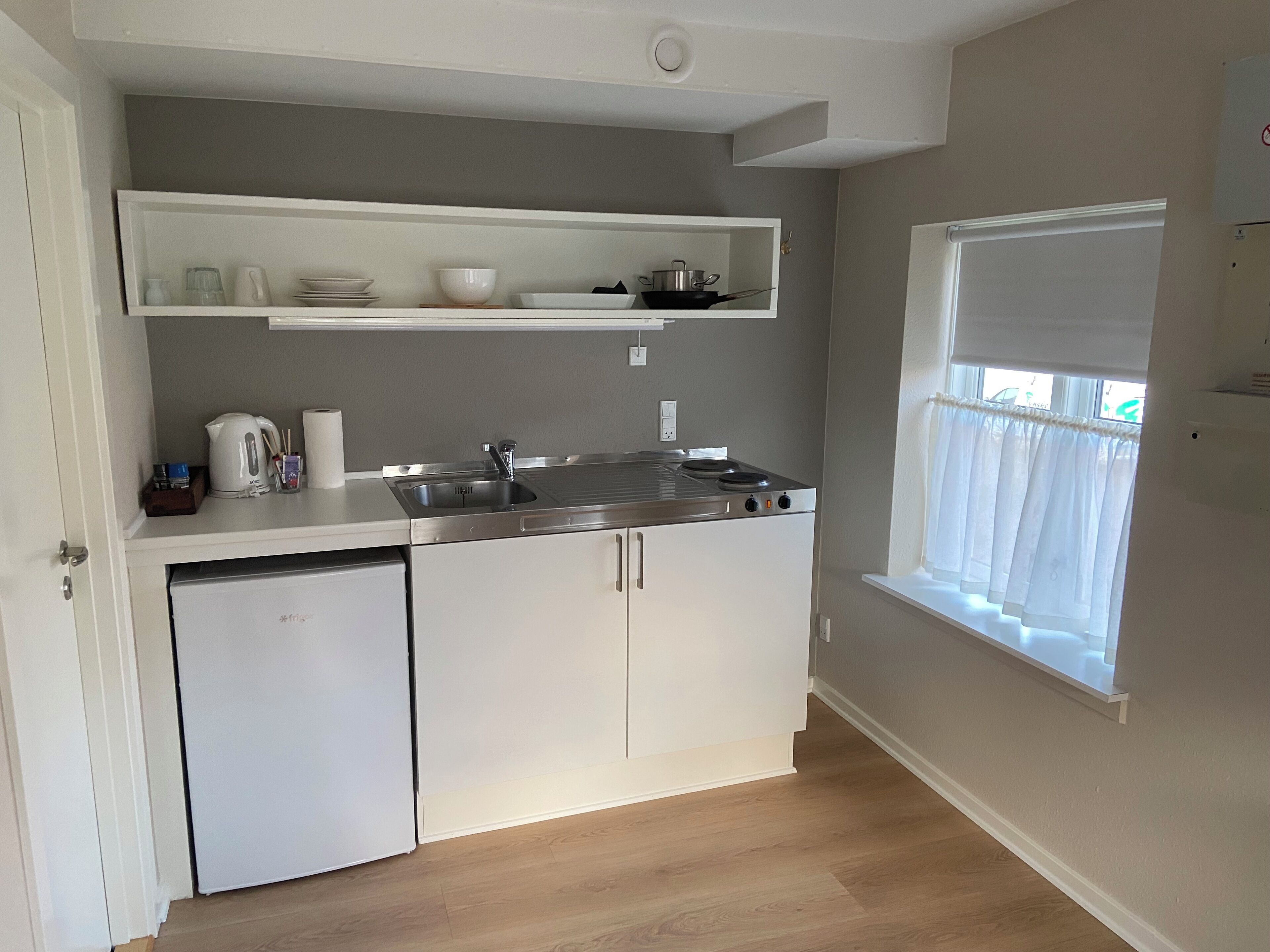 A compact kitchen with a dishwasher, a stove, and a window with a view.