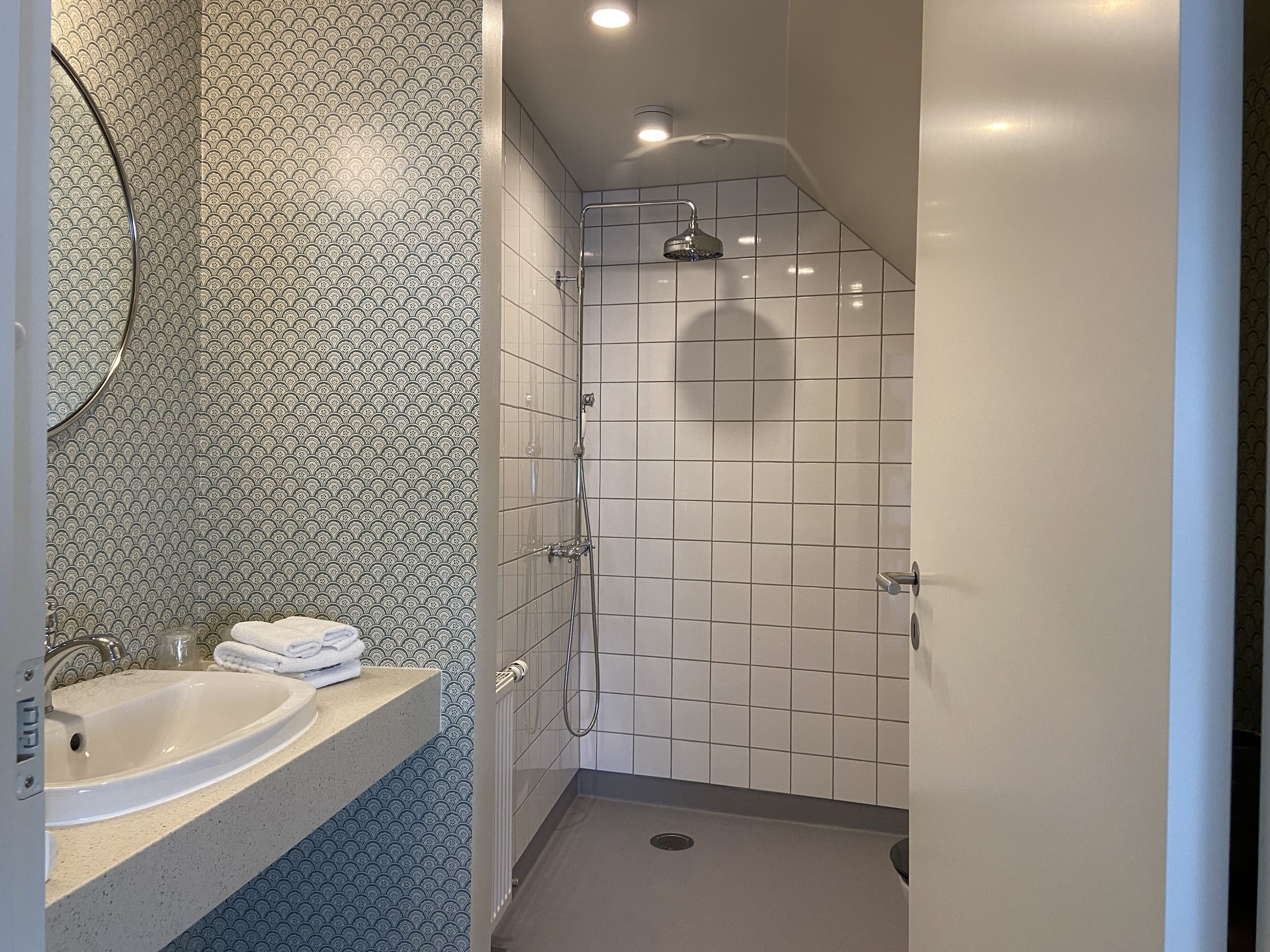 A bathroom with a sink, mirror, and shower.