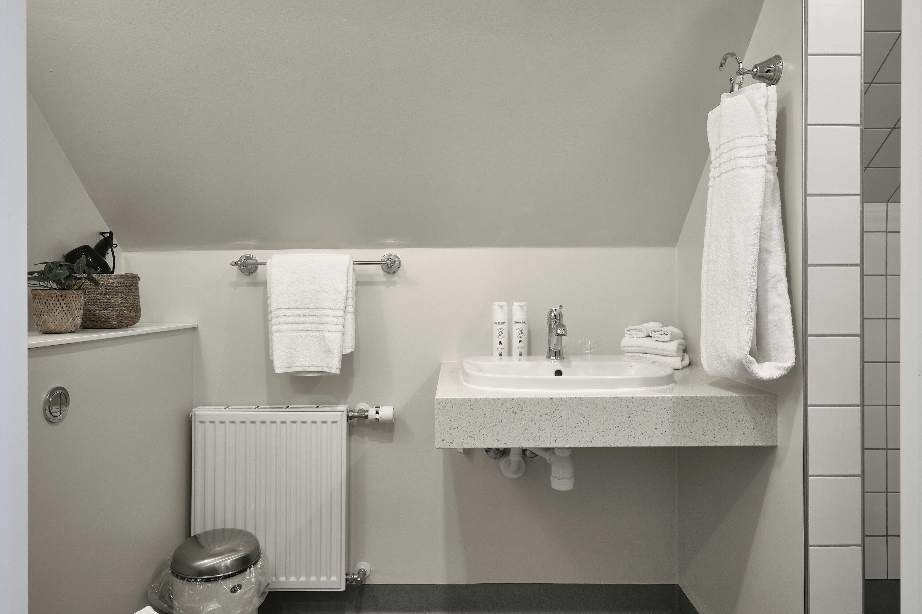 Un baño con lavamanos blanco, toallero y radiador.