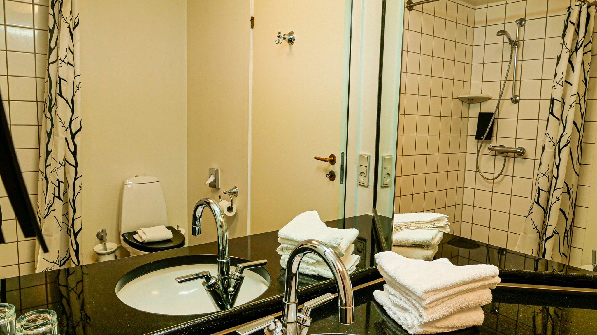 A bathroom with a black sink, a mirror, a toilet, and a shower.