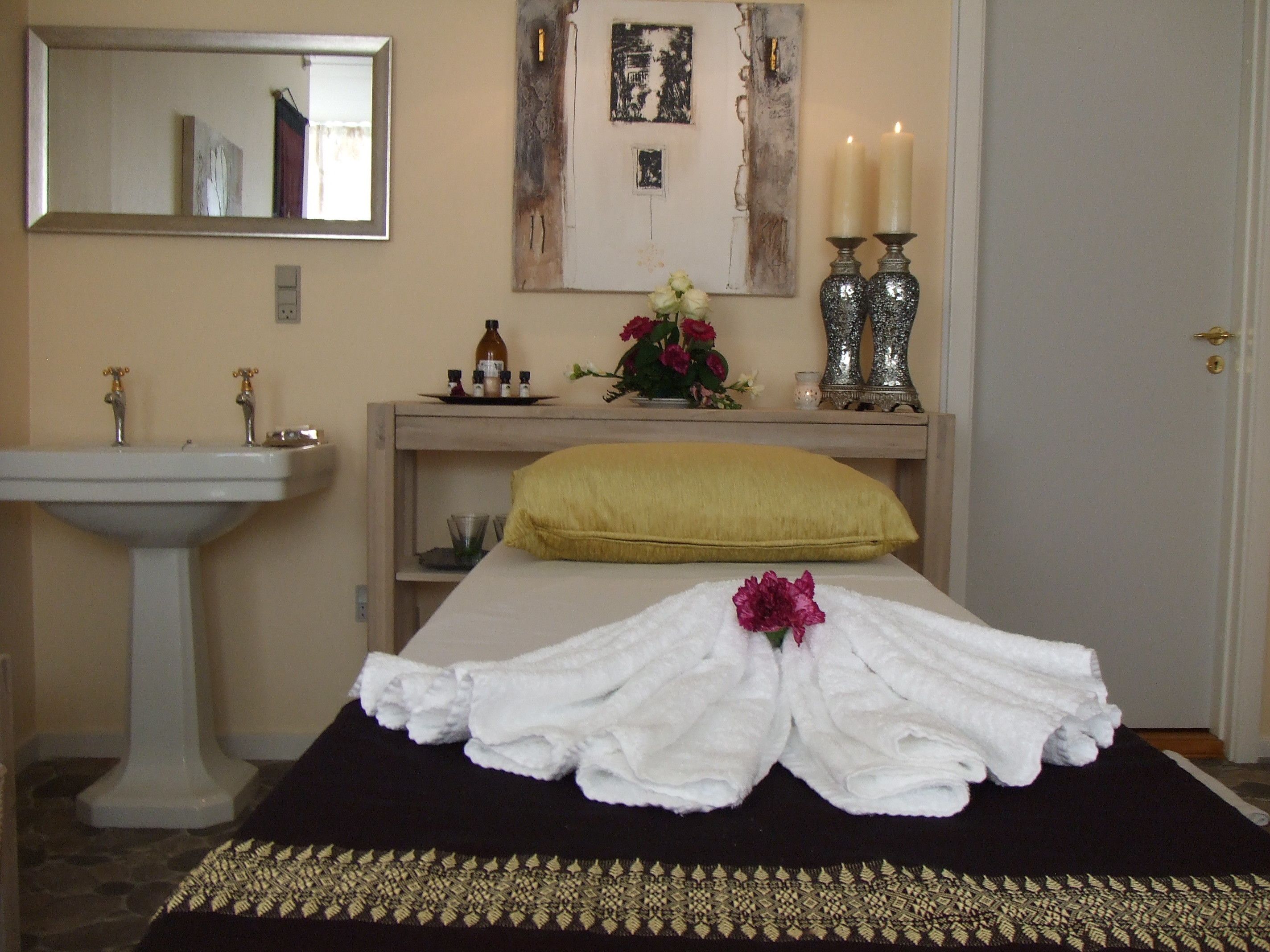 A hotel room with a bed, a bedside table, a mirror, a sink, and a door.