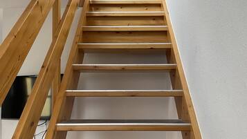 A wooden staircase with a handrail, leading to a landing.