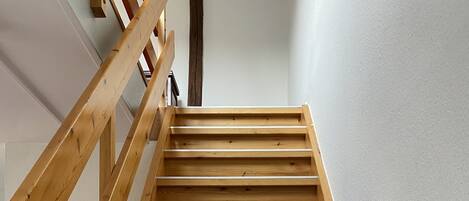A wooden staircase with a handrail, leading to a landing.
