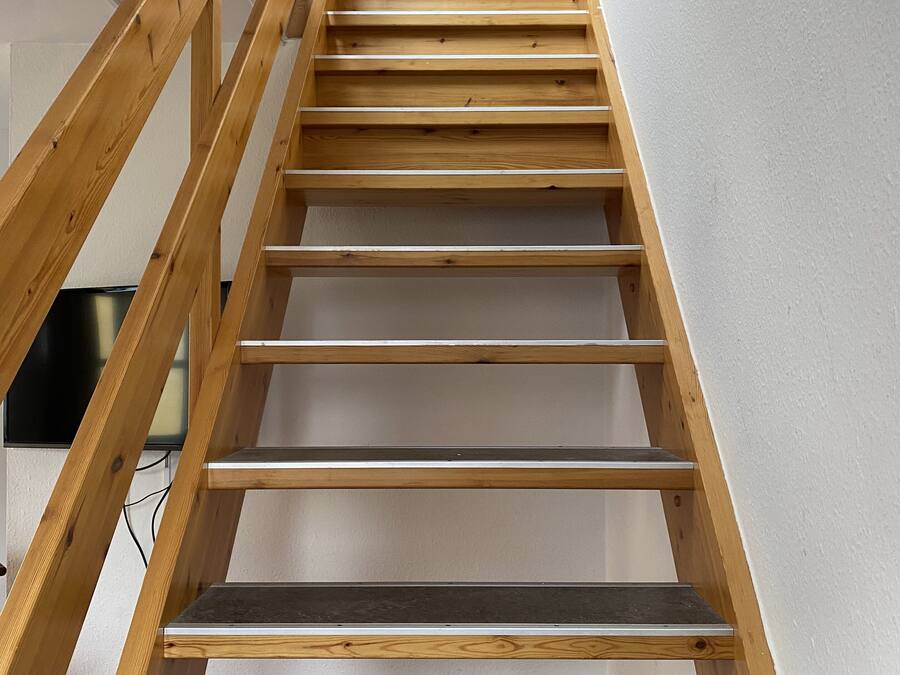 A wooden staircase with a handrail, leading to a landing.