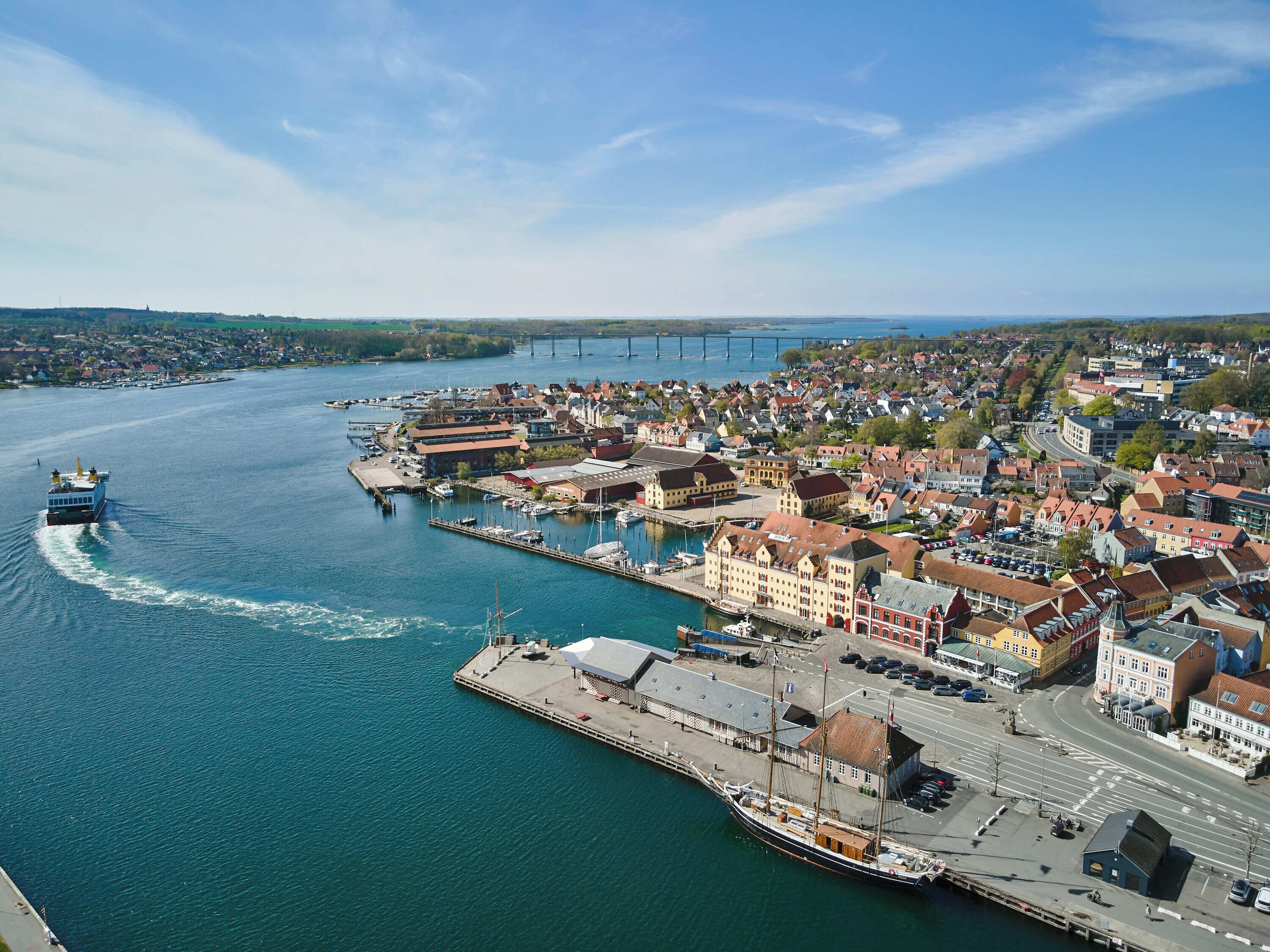 Une ville côtière avec un port, un grand navire et un pont en arrière-plan.