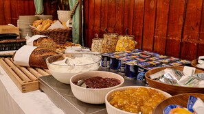 A buffet table with various food items including bread, yogurt, and condiments.